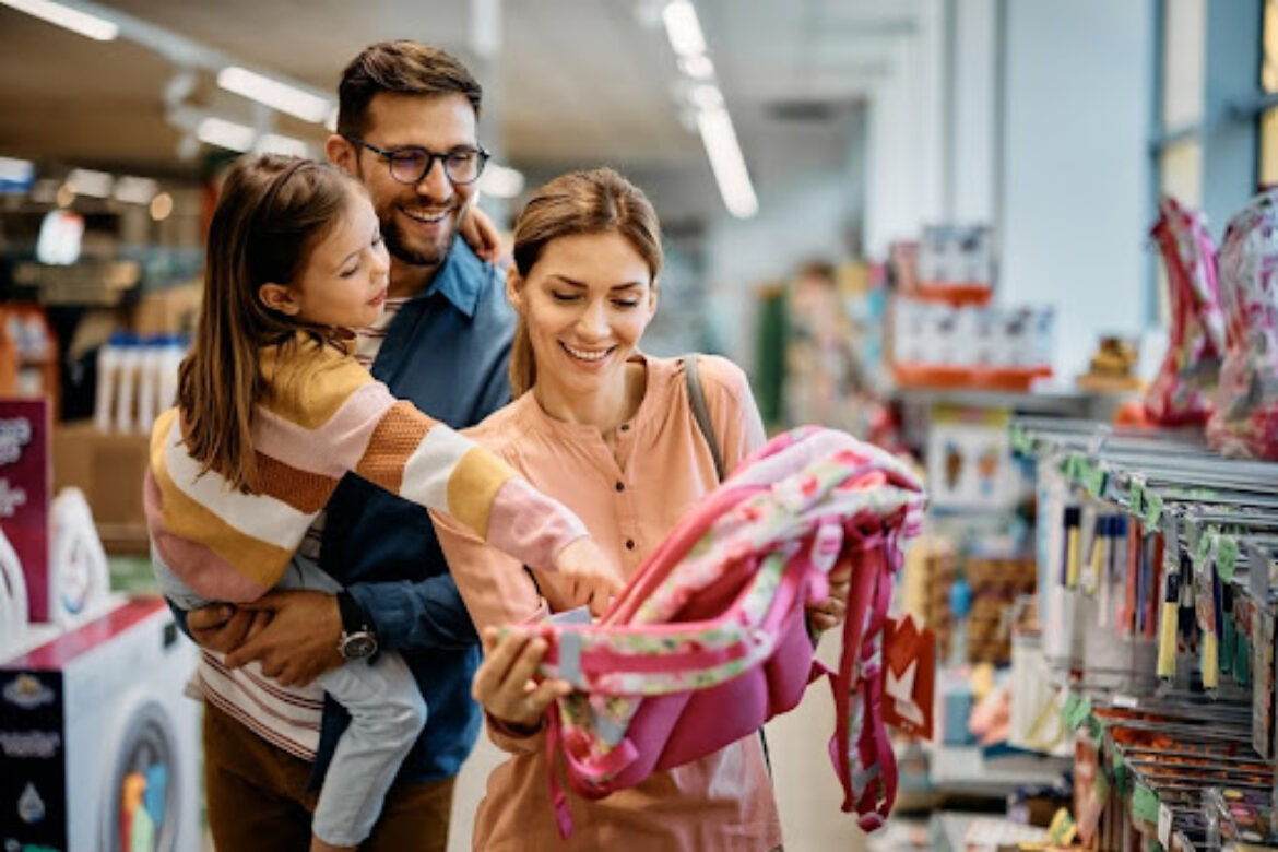 couple and their daughter looking at a school backpack in a store