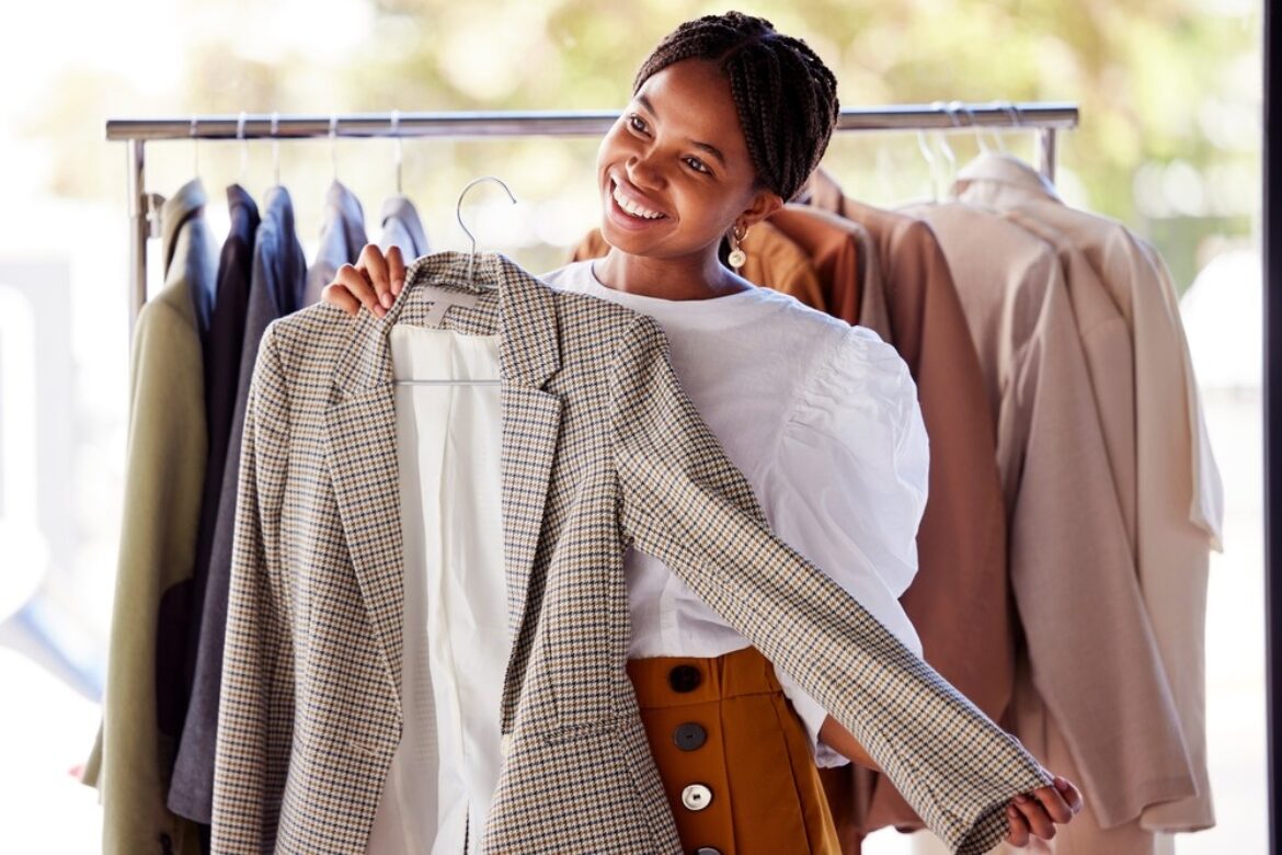 Woman holding up a blazer in front of her that she got off the clothes rack.