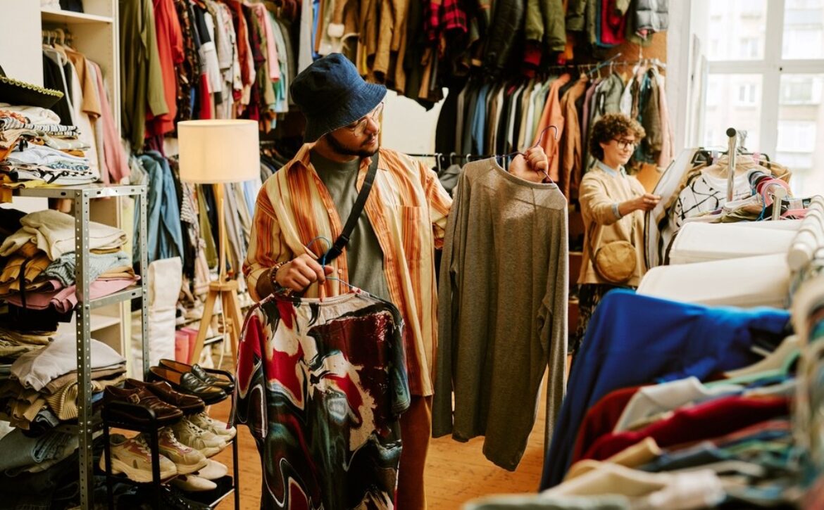 Man and woman looking at different pieces of clothing in a thrift store.