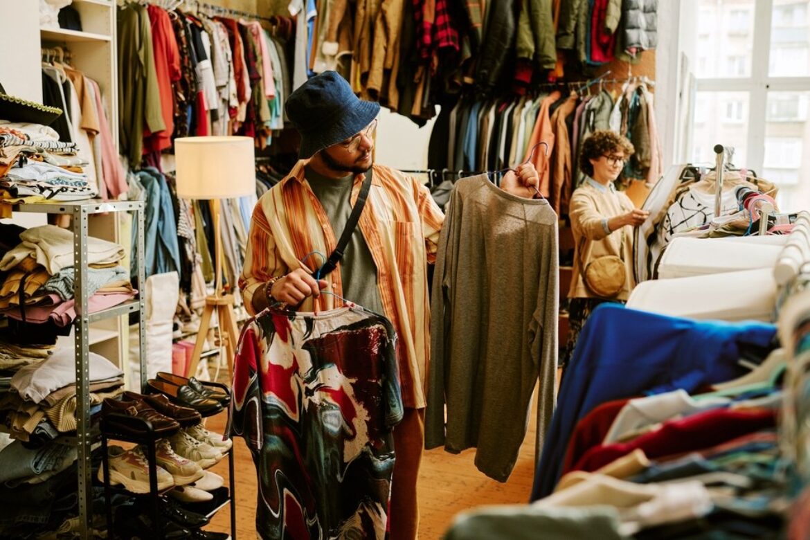 Man and woman looking at different pieces of clothing in a thrift store.