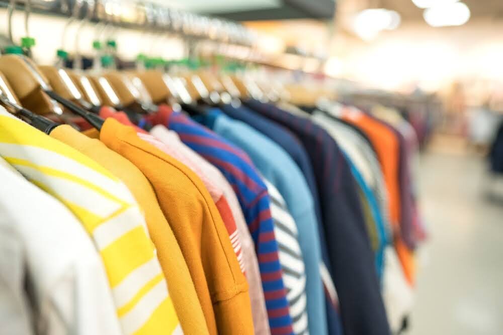 closeup of a row of colorful sweaters on hangers in a thrift store