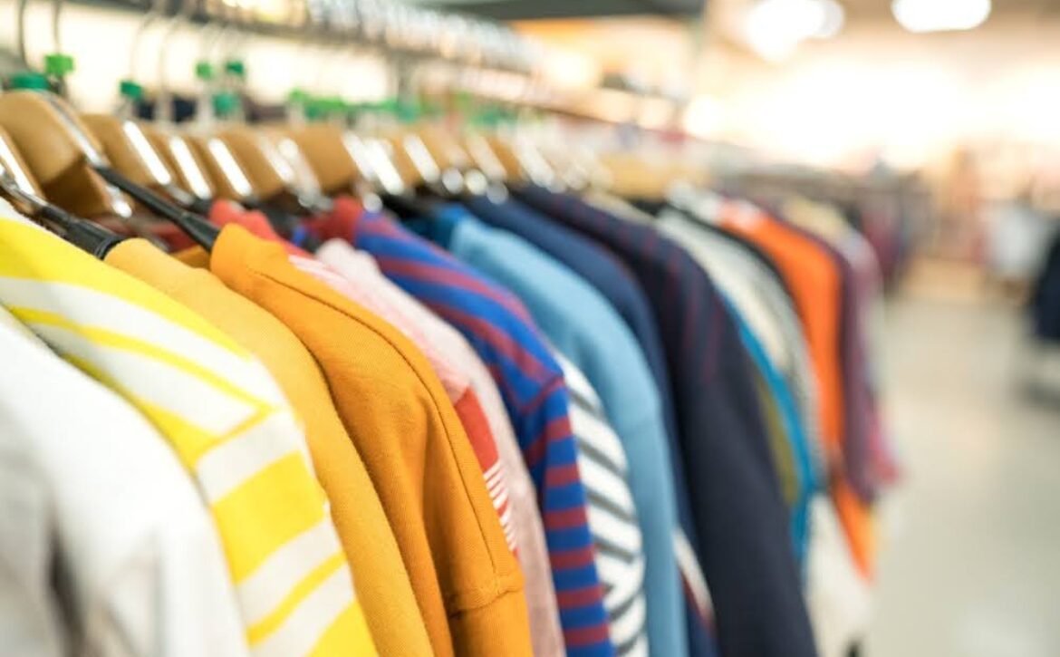 closeup of a row of colorful sweaters on hangers in a thrift store