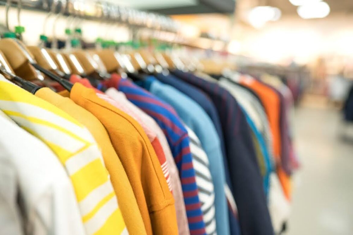closeup of a row of colorful sweaters on hangers in a thrift store
