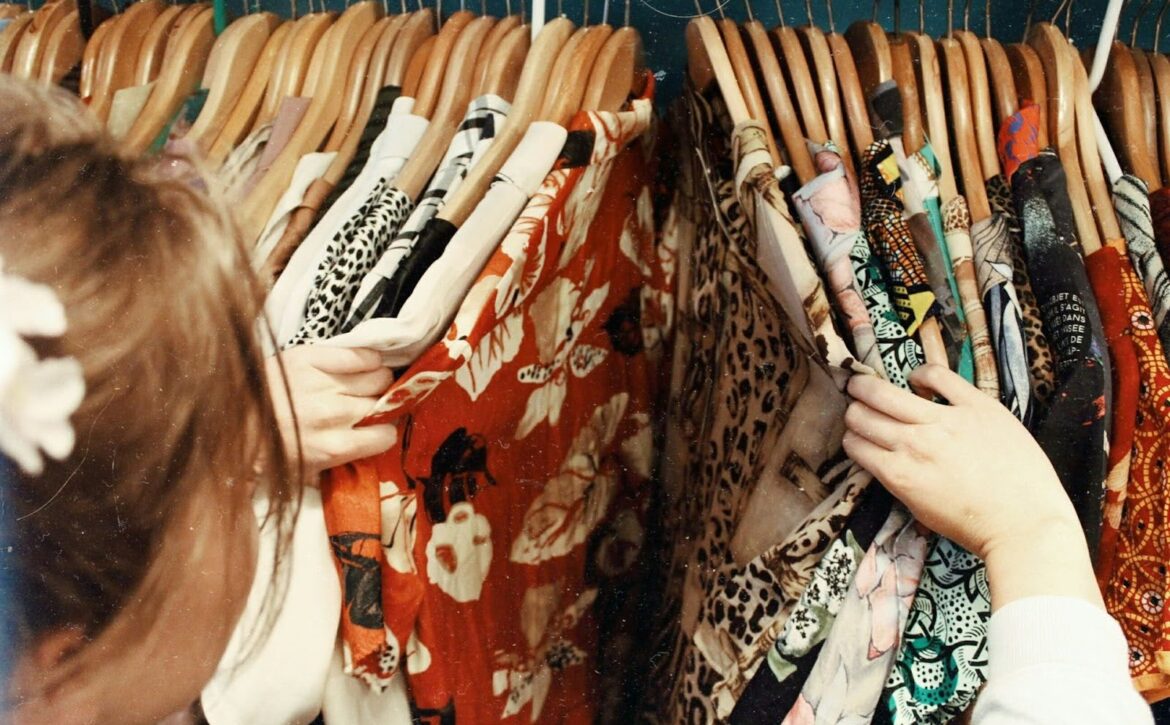 over the shoulder image of a woman sorting through shirts on a clothes rack