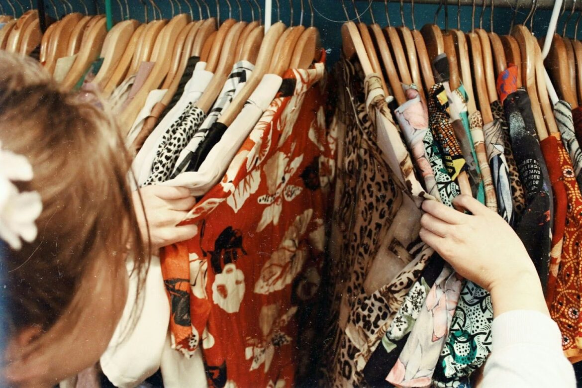 over the shoulder image of a woman sorting through shirts on a clothes rack